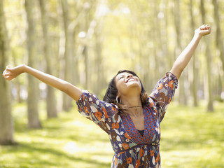 Hispanic woman with arms outstretched in park