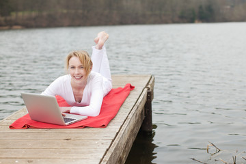 junge frau mit laptop am see