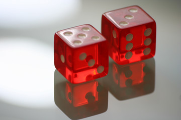 Two red dice on a glass with reflection