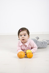 Toddler girl lying on floor with fruits