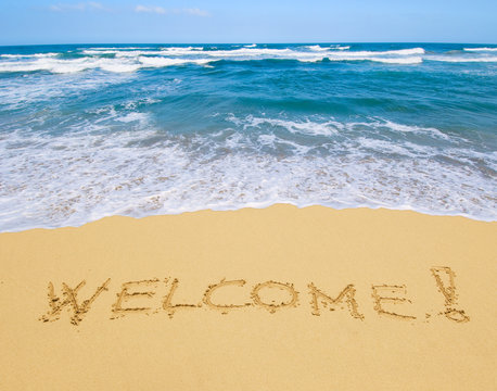 welcome written in a sandy beach