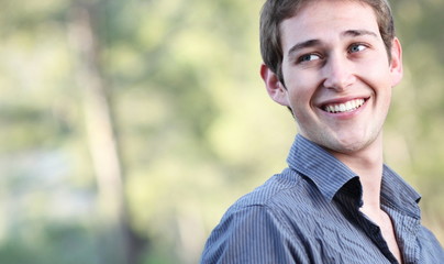 Portrait of a handsome young man smiling while outdoors in a par