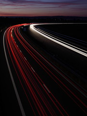 Cars in a rush moving fast on a highway (speedway) at dusk