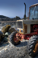 Frontside of old, rusty tractor on a pebble beach