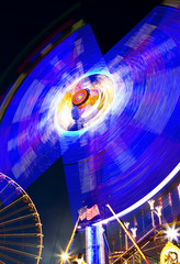 Karusell bei Nacht mit Leuchtspur und Riesenrad