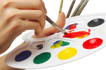 Hand with brush and paints on the palette