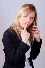 Business woman with mobile phone and finge on mouth - obrazy, fototapety, plakaty