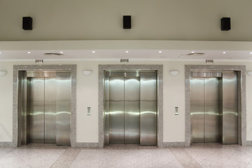 Three elevator doors in corridor of office building