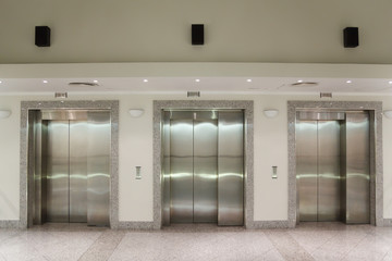 Three elevator doors in corridor of office building © Pavel Losevsky