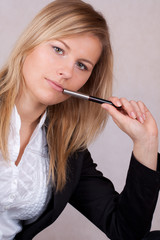 Beautiful business woman with ballpen in mouth - obrazy, fototapety, plakaty