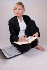 Young business woman writing notes with laptop