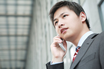 a yong Asiatic businessman  is answering phone outdoor