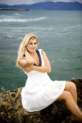 Fototapeta na wymiar Young beautiful fresh woman sitting on a stone near the sea