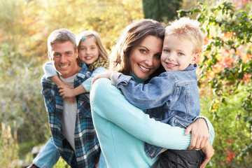 Family Group Outdoors In Autumn Landscape With Parents Giving Ch