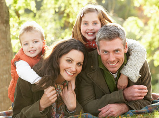 Family Group Relaxing Outdoors In Autumn Landscape
