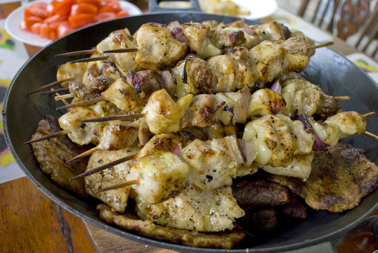 Meat on a stick on a table surrounded by food