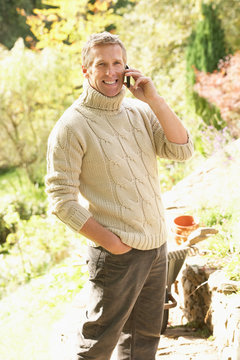 Man Outdoors On Mobile Phone With Dog Whilst On Break From Garde