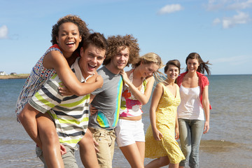 Group Of Young Friends Walking Along Summer Shoreline