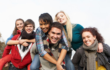 Fototapeta premium Group Of Teenage Friends Having Piggyback Rides In Autumn Landsc