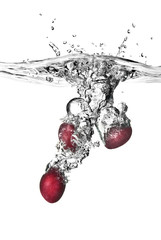 plum dropped into water with bubbles isolated on white