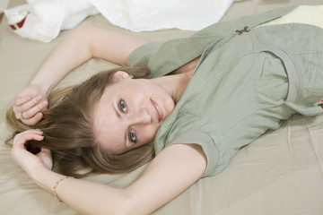 Obraz na płótnie Canvas blond serious woman with long hair lying on bed