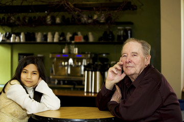 Elderly man and granddaughter at coffee shop restaurant together