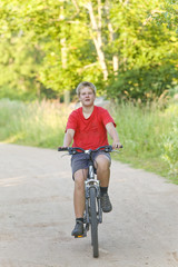 Naklejka premium Teenager goes on bicycle on country road