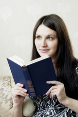 Woman, who reads book sitting on the sofa