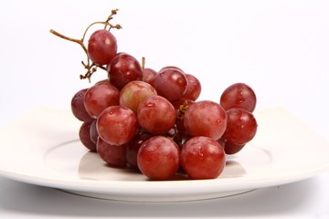 Red grapes on a plate on white background