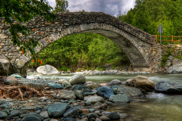 Ponte romano su torrente di pietre in alta montagna