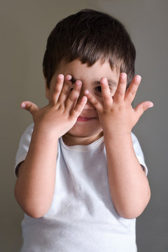 bambino che gioca con le mani in viso