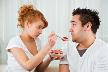 young, beauty girl feeding a handsome boy strawberry