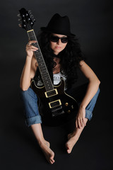 Fototapeta na wymiar Girl in sunglasses sitting on the floor with a guitar