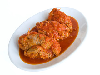 Meat roulade in tomato sauce on white dish.