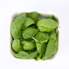 Basil leaves in a small white bowl