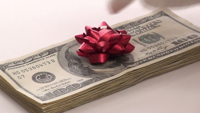 Santa puts bow on stack of hundred dollar bills V1 - HD