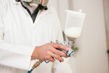 Lackierer arbeitet mit Sprühfarbe und Pistole