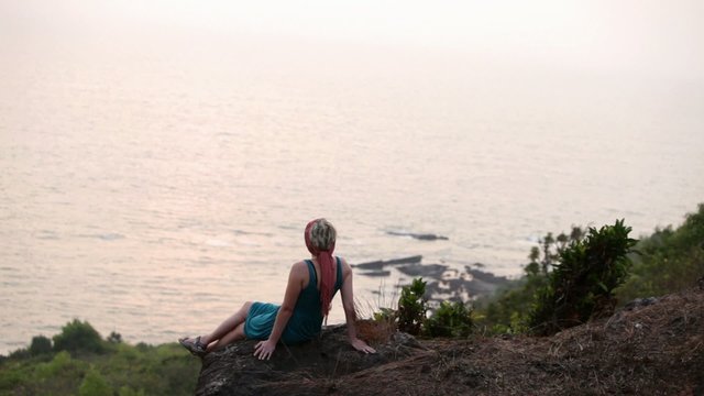 woman relaxing on a hill and watching the sunset in Goa,India.