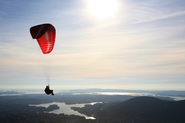Paraglider flying over Norwegian landscape