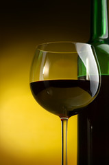 Bottle and glass of wine on a yellow background