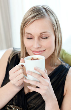 Relaxed woman drinking a coffee sitting on a sofa