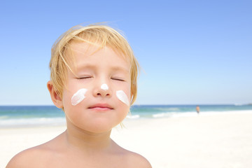 cute child with sunscreen  at the beach