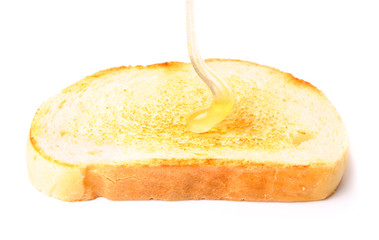 honey pouring down to white bread. isolated on white