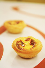 two egg tarts of various flavors on a table..