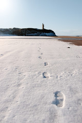 footprints in snow on empty beach with castle