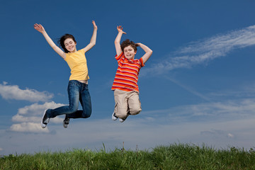 Fototapeta na wymiar Girl and boy jumping, running against blue sky