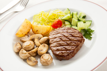 Grilled steaks with chips and vegetables