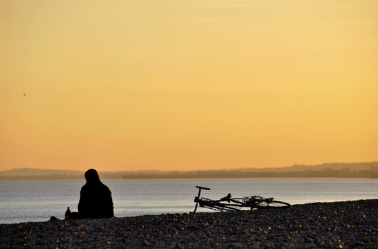 A cyclist sitting and contemplating the sea