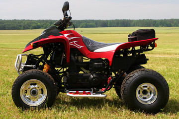 Obraz premium Red quad bike (ATV) on green field.