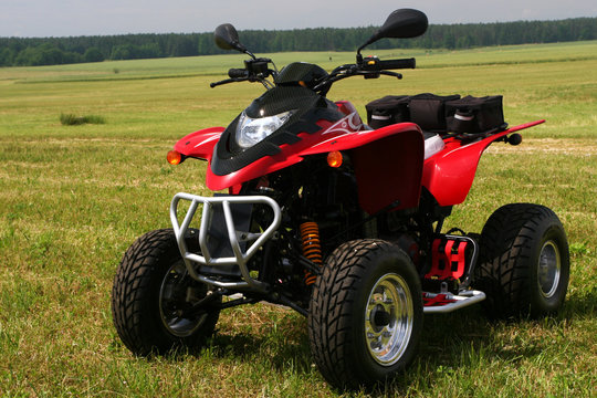 Red quad bike (ATV)  on green field.